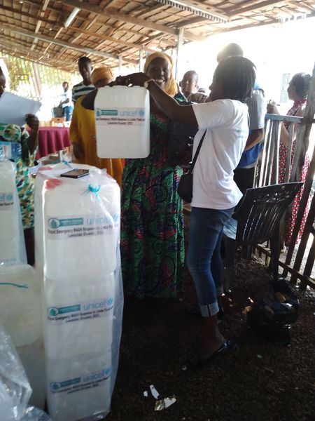 A WASH container is handed to a community member during relief distribution